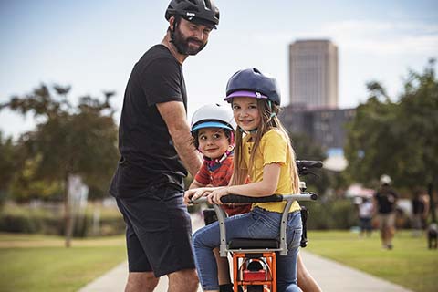 Un papa promène sa fille et son fils dans le parc sur un vélo Kombi E5